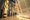 Quelques personnes dans une galerie de musée explorent de grands panneaux de bois décorés de figures d’animaux et d’œuvres perlées métisses. À droite, on voit des lattes de bois placées horizontalement et courbées.