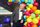 Un artiste portant un complet se tient devant des ballons multicolores. 