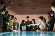 Un groupe de jeunes debout autour d’une table dont la surface interactive émet une lumière bleue et blanche.