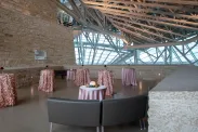 Une terrasse en pierre de Tyndall décorée pour une réception avec des nappes en satin rose pâle recouvrant des tables de cocktail et des canapés en cuir brun.