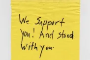 A piece of cloth with "We support you! And stand with you." written.