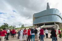 Un groupe de personnes regardant une chorale qui chante sur les marches de l’amphithéâtre extérieur du Musée.