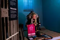 Un homme portant une coiffe en plumes d'aigle et tenant une pipe est agenouillé sur une fourrure dans une pièce ressemblant à une petite cellule de prison.