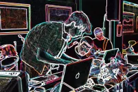 Quatre personnes autour d’une table recouverte d’ordinateurs et d’équipement de musique électronique. La photo a été modifiée de façon à ce que l’arrière-plan soit noir et les éléments de la photo, surlignés en néon multicolore.