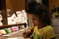 Une fille écrivant sur une feuille de papier avec un crayon.