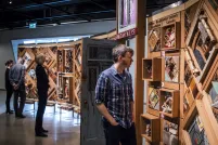 Deux personnes regarde une grande oeuvre d'art composée d'objets fixés dans des cadres de cèdre; il y a une porte ouverte au centre de l'oeuvre.