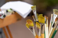 Des pinceaux d'artiste de diverses tailles, longueurs et couleurs, dans un contenant en métal.