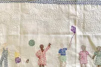 Une pièce de tissu brodée montrant des familles habillées de diverses tenues culturelles et participant à des activités.