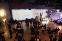 Une foule de personnes regarde un groupe musical qui joue sur une scène bien éclairée.