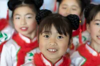 Quatre filles souriantes portant des vêtements assortis en blanc, rouge et vert.