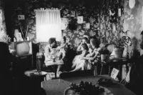 Une image en noir et blanc de femmes et de jeunes enfants assis sur des sofas et des chaises dans un petit salon.