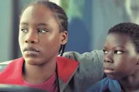 Lokita, une migrante camerounaise de 16 ans, entoure de son bras Tori, un jeune Béninois de 11 ans. Elle regarde ailleurs, l’air tendu et inquiet, tandis qu’il la regarde intensément.