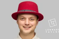 Un homme souriant aux yeux verts porte un chapeau haut de forme en feutre rouge et une chemise à col ivoire avec des boutons-pression noirs.