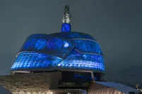 L’extérieur du Musée canadien pour les droits de la personne est photographié de nuit. Le bâtiment est éclairé de l’intérieur par des lumières vives d’un bleu profond.