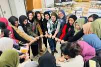 Un groupe de femmes musulmanes souriantes formant un cercle et se tenant par la main.