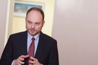 Un homme qui parle, les bras pliés aux coudes et les mains levées, ouvertes l’une face à l’autre.