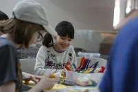 Des enfants d'âges différents sont assis autour d'une table en train de bricoler.