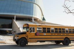 Un autobus scolaire jaune est stationné devant le Musée. 