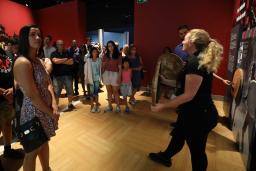 Des personnes debout qui écoutent une guide-interprète du Musée.