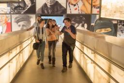 A group of young adults talk excitedly while walking up a set of illuminated ramps.