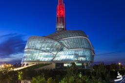 An unusual museum building topped by a glowing red tower.