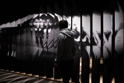 Une personne marche devant une grande photographie de Nelson Mandela.