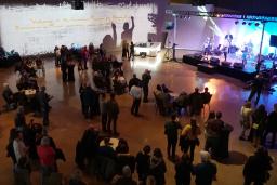 Une foule de personnes regarde un groupe musical qui joue sur une scène bien éclairée.