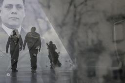 Une image historique translucide d’un homme en complet superposé à une photo contemporaine de deux hommes en silhouette marchant dans un corridor.