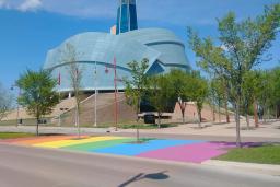 A rainbow crosswalk in front of the Canadian Museum for Human Rights on a sunny day