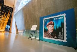 Un grand affichage d'un timbre représentant le sergent Tommy Prince est visible sur le côté droit de l'image. Une passerelle située devant le panneau d'affichage mène à gauche de l'image, dans la galerie Perspectives indigènes.