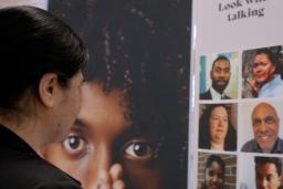 A woman gazes at a display showing faces of a diverse group of people.