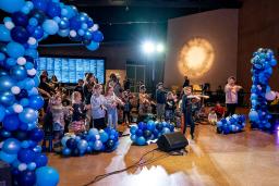 Des jeunes dansent dans une salle remplie de ballons bleus.
