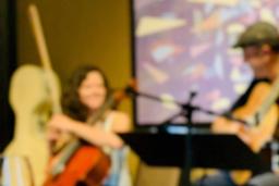 Une violoncelliste et un guitariste discutent et jouent de la musique ensemble dans un café.