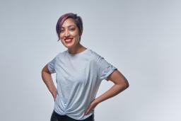 Une femme souriante aux cheveux violets portant un t-shirt.