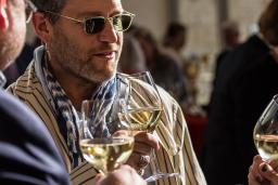 Des invités à une soirée discutent en tenant des verres de vin blanc.