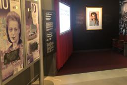 Une exposition muséale qui ressemble à un cinéma de vieux style. D’un côté, on voit de grandes images représentant un billet canadien de 10 $ sur lequel figure le visage d’une femme.