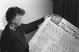 Une personne tient une grande feuille de papier recouverte de texte et dont le gros titre est « The Universal Declaration of Human Rights. »