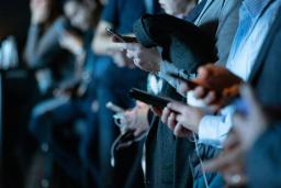 Un groupe de personnes utilisant leurs téléphones portables debout.