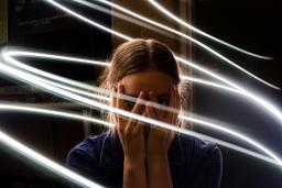 Une adolescente se couvre le visage de ses mains et regarde à travers ses doigts, l’air bouleversée. Des lignes lumineuses tourbillonnent autour d’elle.