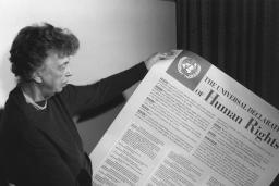 Une personne tient une grande feuille de papier recouverte de texte et dont le gros titre est « The Universal Declaration of Human Rights. »