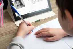 Un jeune étudie à la maison avec une tablette et fait des devoirs.