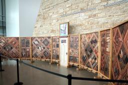 Vue de droite d’une structure de panneaux de bois verticaux recouverts de motifs d’images, avec une porte blanche au centre.