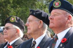 Trois hommes âgés, membres de la Légion canadienne, sont assis côte à côte. Tous les trois portent le coquelicot du jour du Souvenir sur leur uniforme.