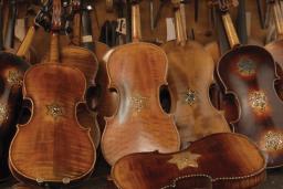 Plusieurs violons restaurés sont présentés appuyés les uns sur les autres dans une pile. Chacun des violons porte au moins une étoile de David.