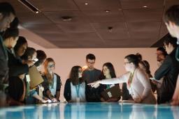 Un groupe de jeunes debout autour d’une table dont la surface interactive émet une lumière bleue et blanche.
