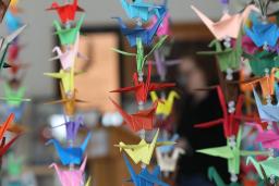 Des grues en papier coloré en origami sont suspendues en rangées verticales.