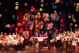 La chorale Rainbow Harmony Projet chantant sur une scène en bois dans une église.