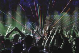 Une foule lors d'un concert avec des rayons multicolores sur un fond tacheté de bleu et de vert.