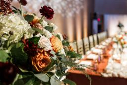 Un bouquet de roses se trouve au premier plan et un arrangement de table d’honneur est à l’arrière-plan.