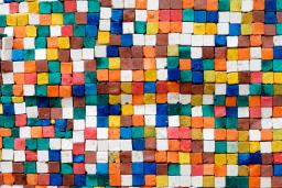 Des tuiles carrées de différentes couleurs et placées de manière aléatoire sont photographiées d'en haut, ce qui crée un effet de pixellisation.